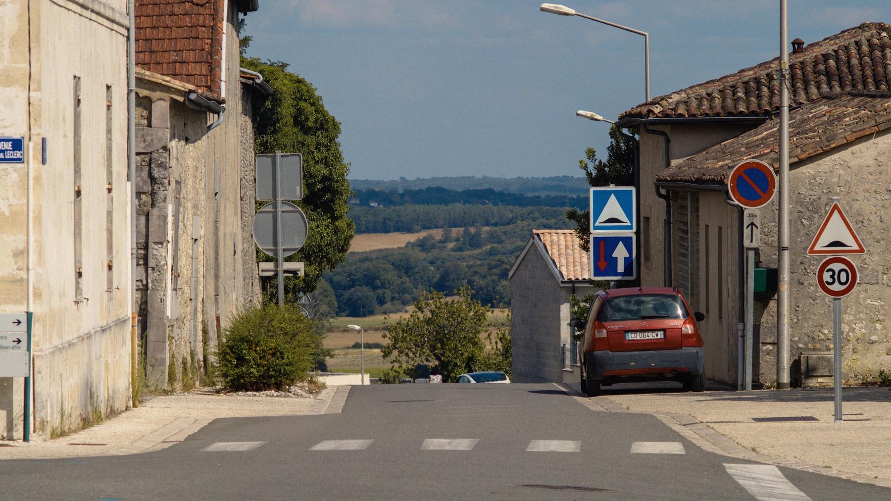 Un homme marche sur une petite route de campagne, au sommet d'une montée.