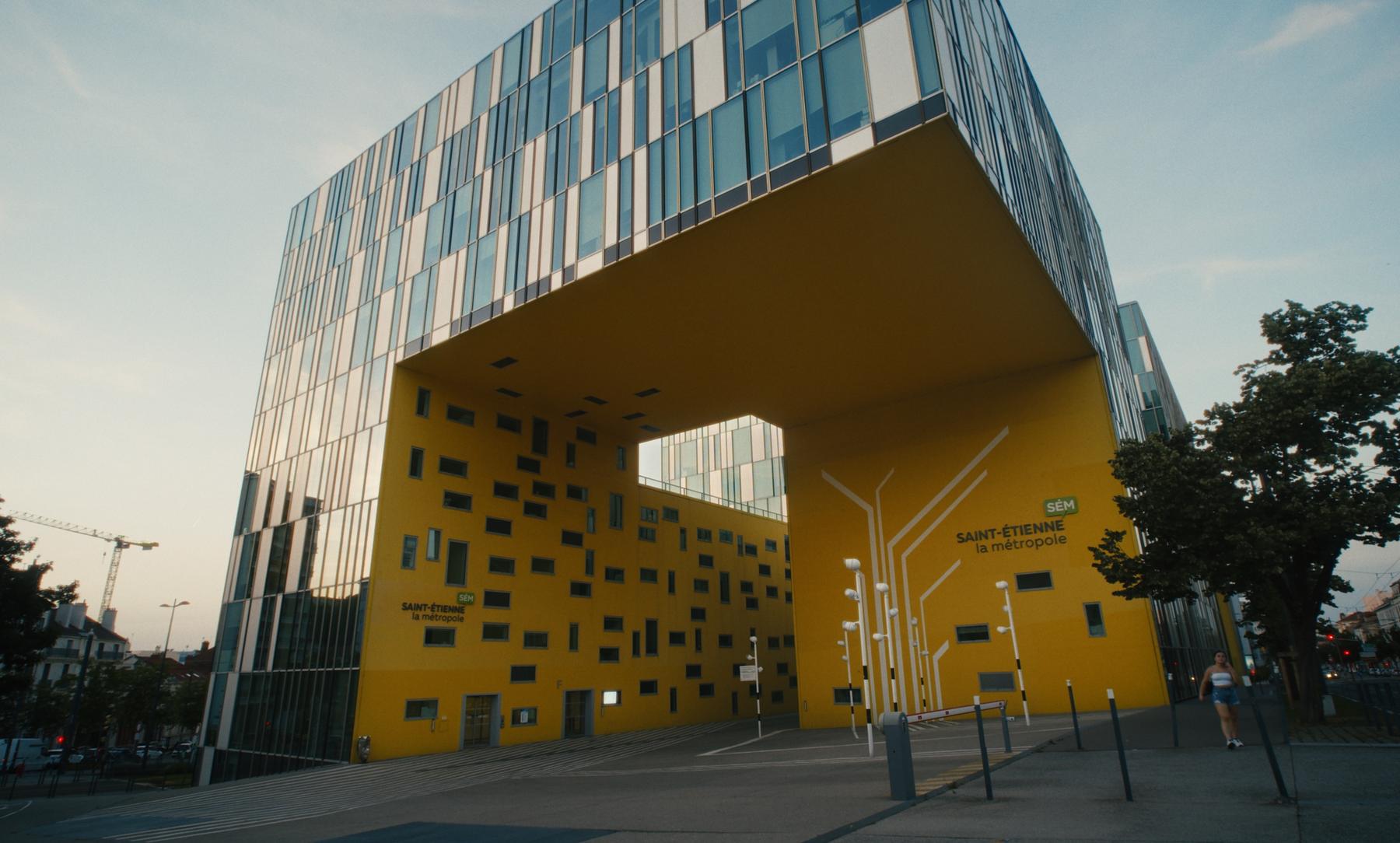 Le bâtiment jaune de Saint-Étienne Métropole au crépuscule.