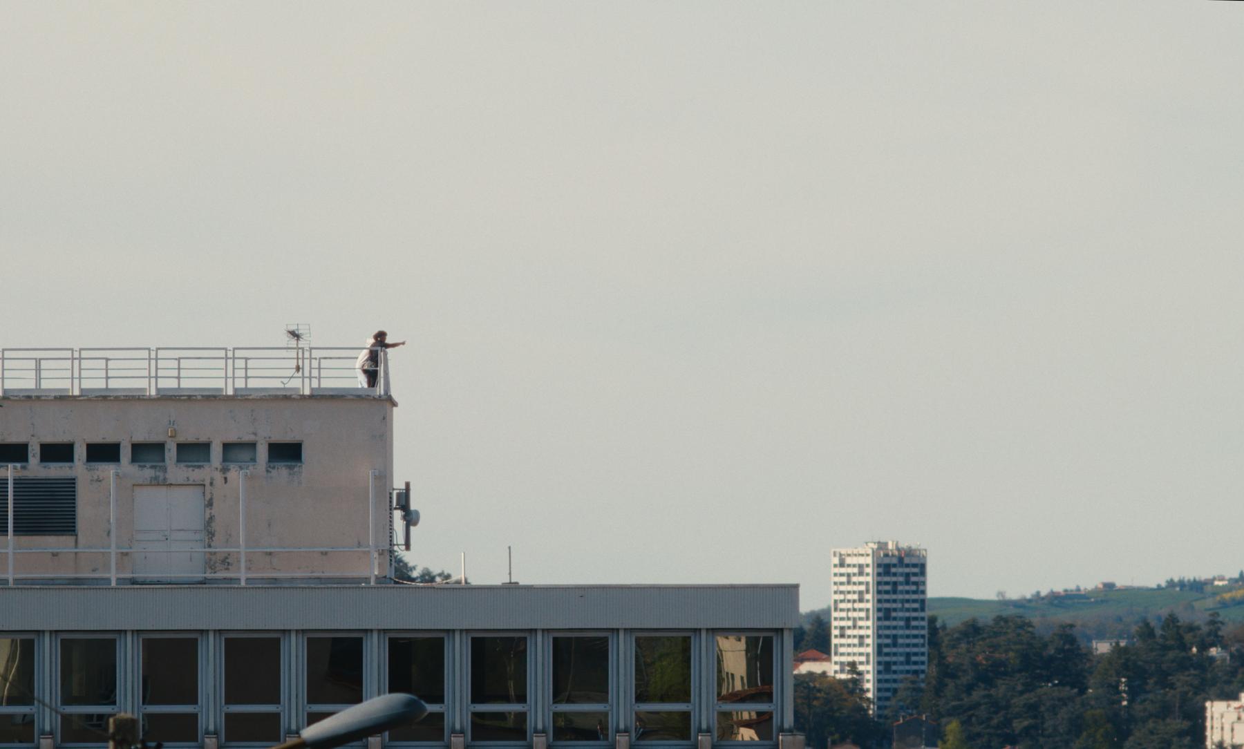 Photogramme de Sainté : sur un toit, une silhouette pointe l'horizon du doigt.